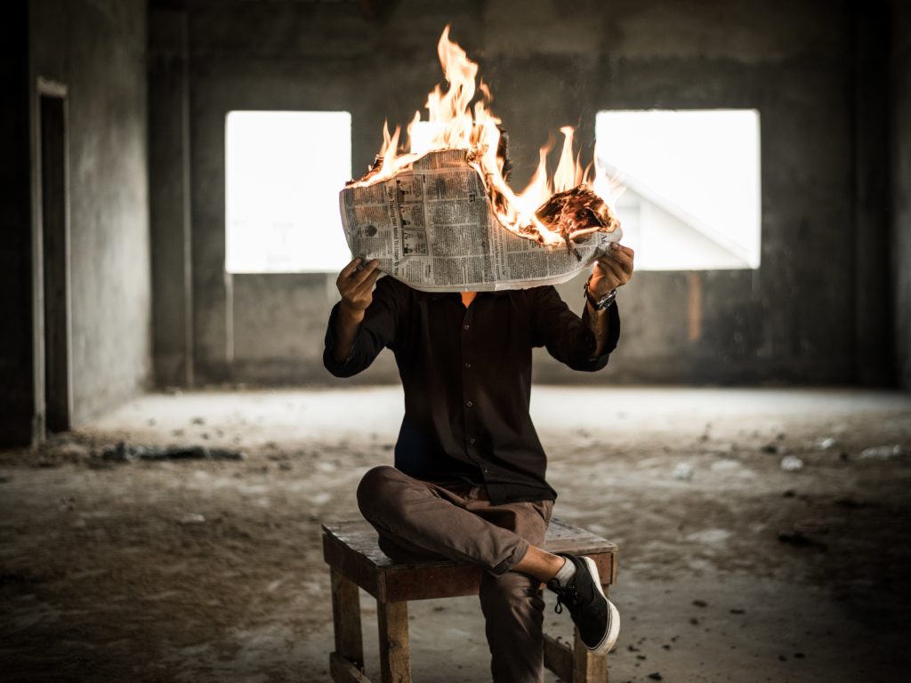 Man holding burning newspaper